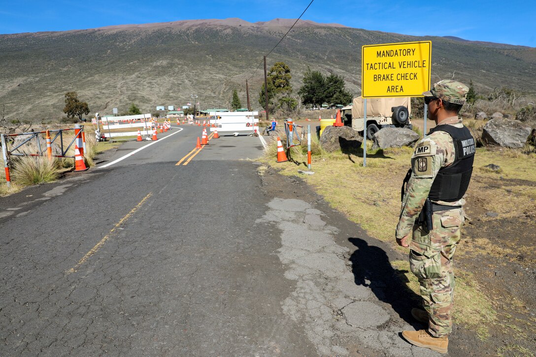 A 728th Military Police Battalion Soldiers monitors gate traffic safety while on patrol during a law enforcement operation on Pohakuloa Training Area, Hawaii, Dec. 9, 2022. The “Warfighters” Battalion Soldiers were tasked to assist Department of the Army (DA) Civilian Police officers on PTA, in response to increased road traffic due to a nearby volcanic eruption.