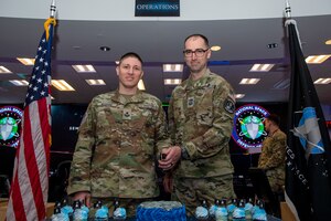 Two men in military uniforms cut a cake