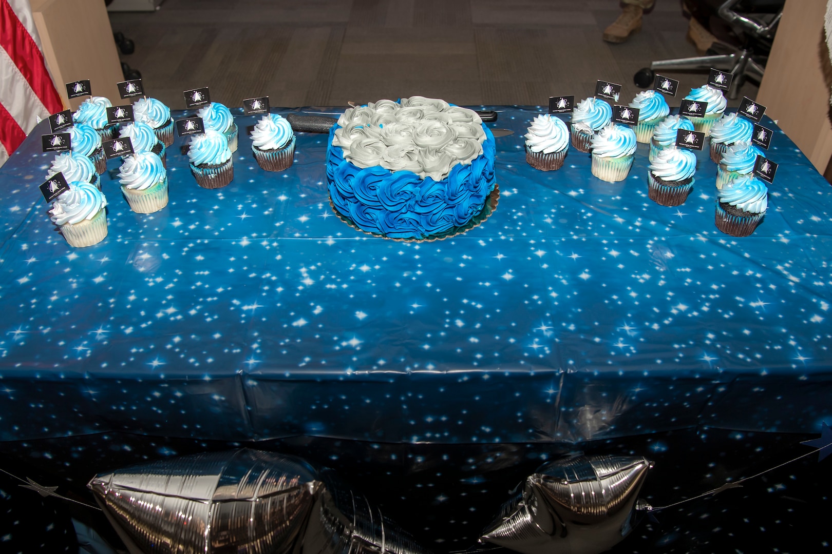 Cake and cupcakes sit on top of galaxy table cloth