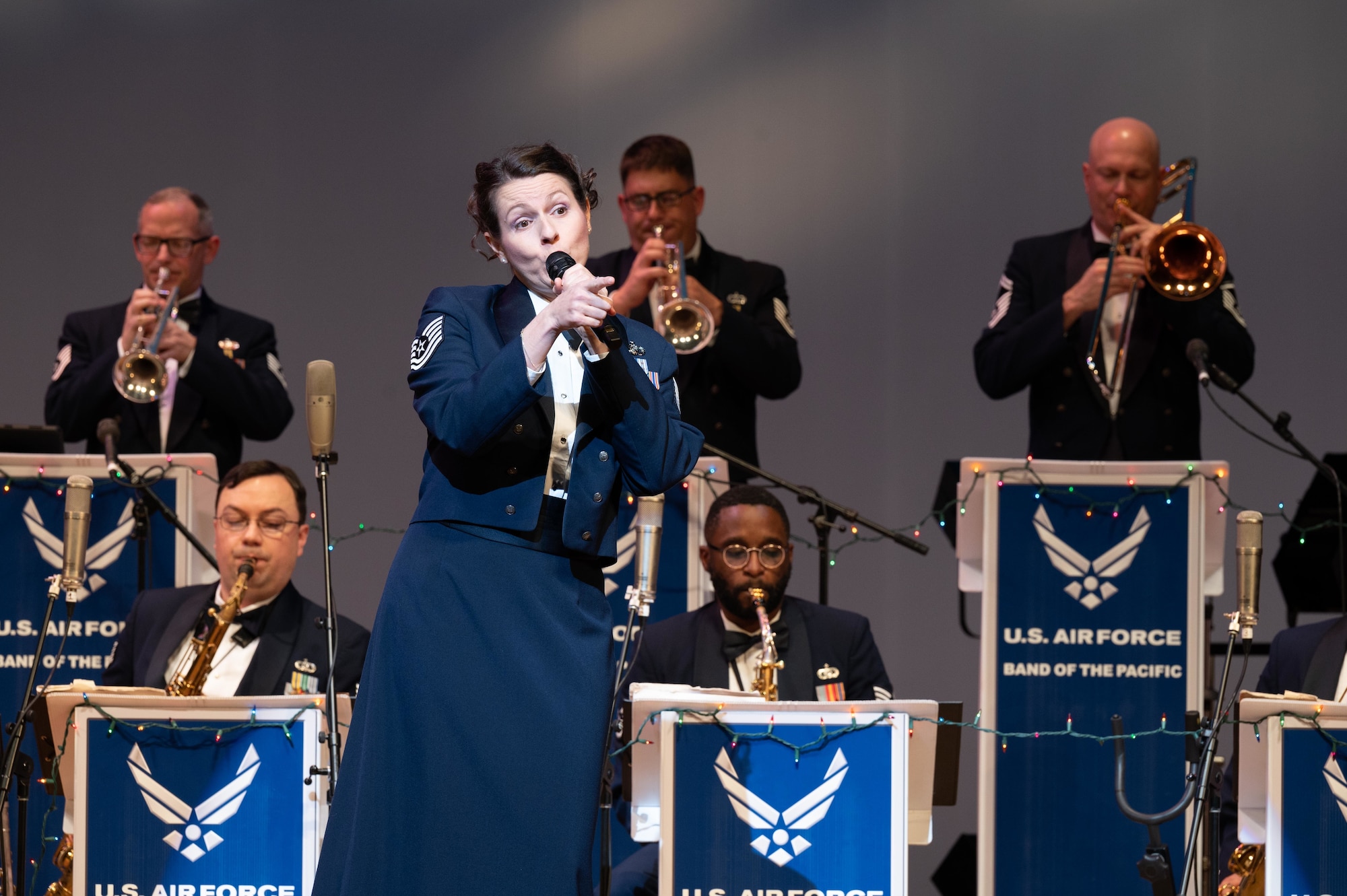 A PACAF band member sings into a microphone during the Christmas Big band Concert