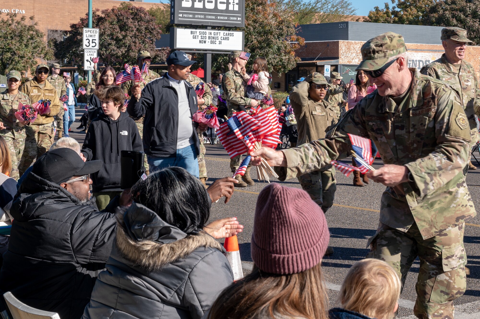 U.S. Air Force Brig. Gen. Jason Rueschhoff, 56th Fighter Wing commander hands out American Flags souvenirs during the Fiesta Bowl Parade, Dec. 17, 2022, in Phoenix, Arizona.
