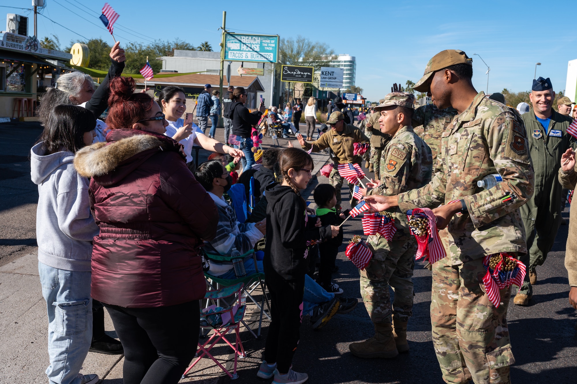 U.S. Air Force Airmen hand out American Flags souvenirs during the Fiesta Bowl Parade, Dec. 17, 2022, in Phoenix, Arizona.