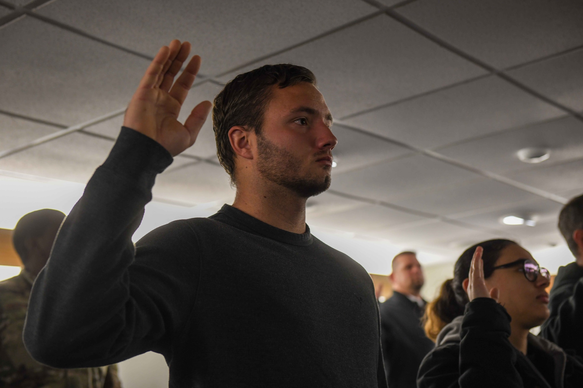Aiden Killey, an employee at Windy Trails Golf Course on Altus Air Force Base, Oklahoma, raises his hand for the oath given by Col. Blaine Baker, 97th Air Mobility Wing commander on Dec. 19, 2022. Baker emphasized the civilians who took the oath were not swearing allegiance to a person or a place, but to the constitution of the United States of America. (U.S. Air Force photo by Airman 1st Class Kari Degraffenreed)