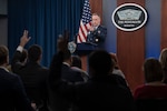 A service member stands at a lectern and points to a man whose hand is raised.