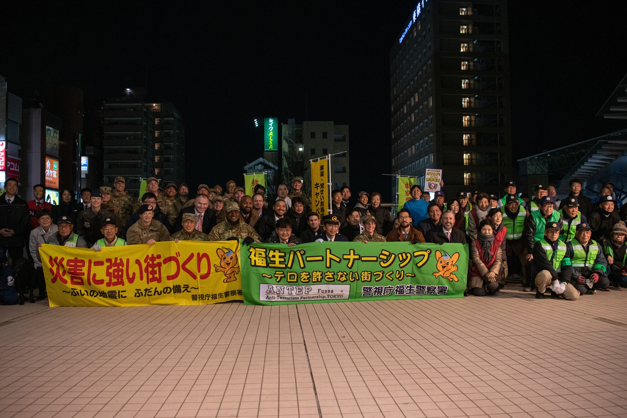 Yokota Air Base leadership and community members pose for a group photo while holding banners