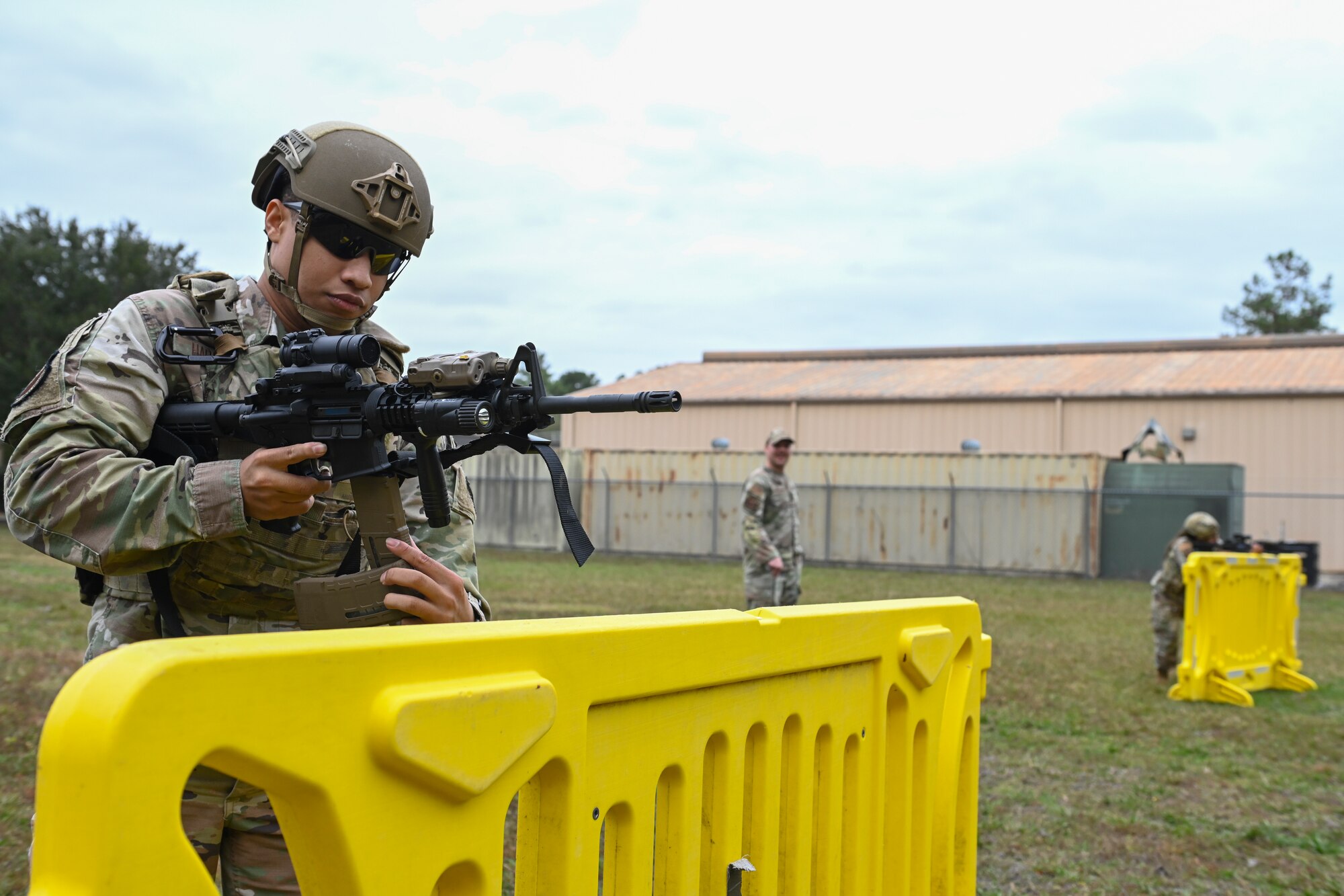 A photo of two Airmen standing in front of yellow barriers.