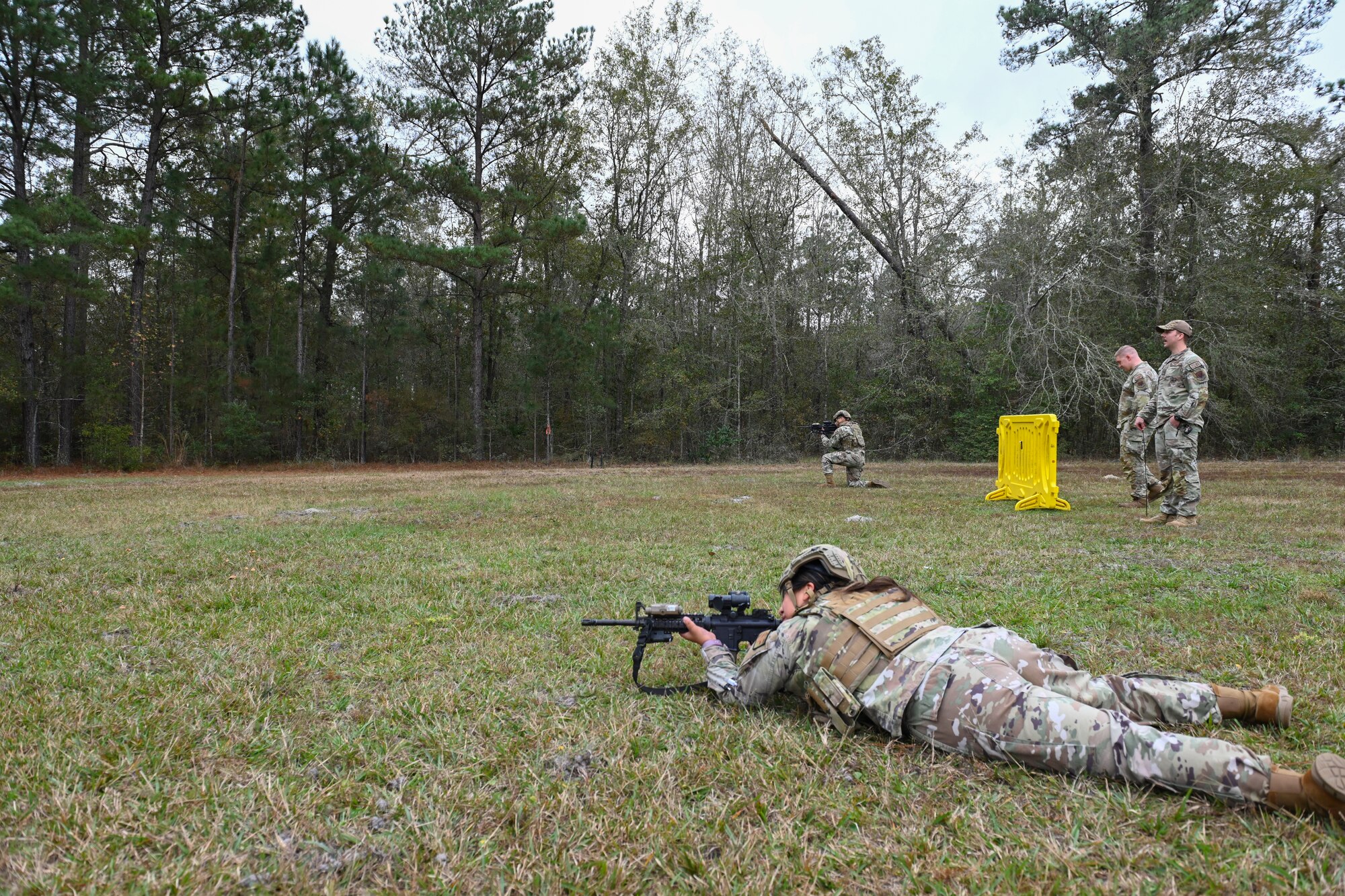 A photo of an Airman laying in prone position in the foreground and an Airman in kneeling position in the back ground aiming toward a target.