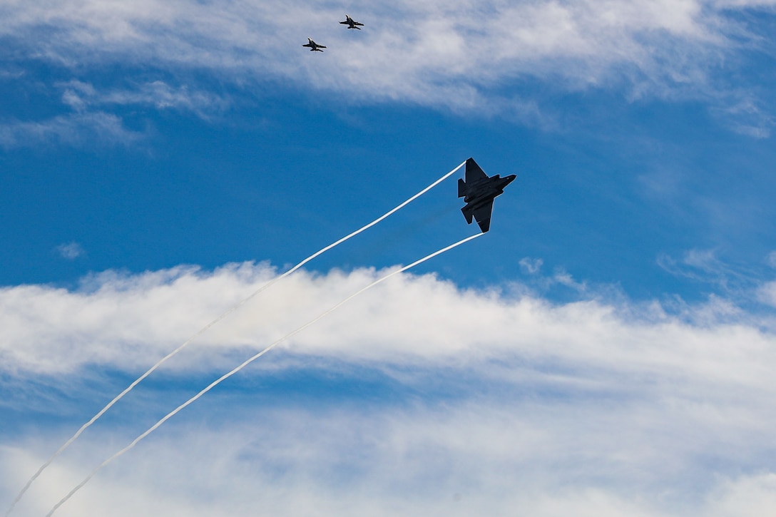 Aircraft fly across a partly cloudy sky.