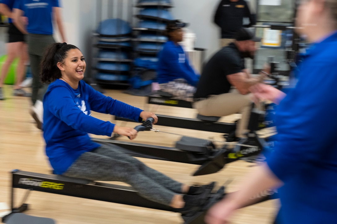 An athlete smiles as she practices rowing on an erg.