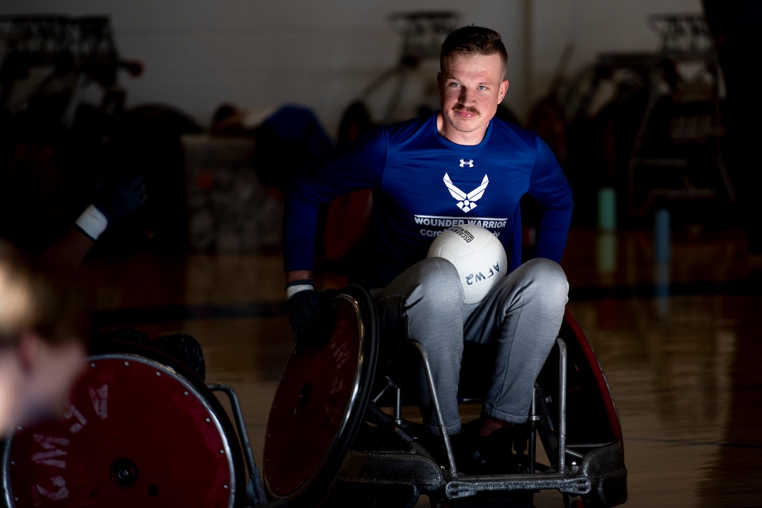 A wheelchair rugby player is lit up by a sun beam during practice.