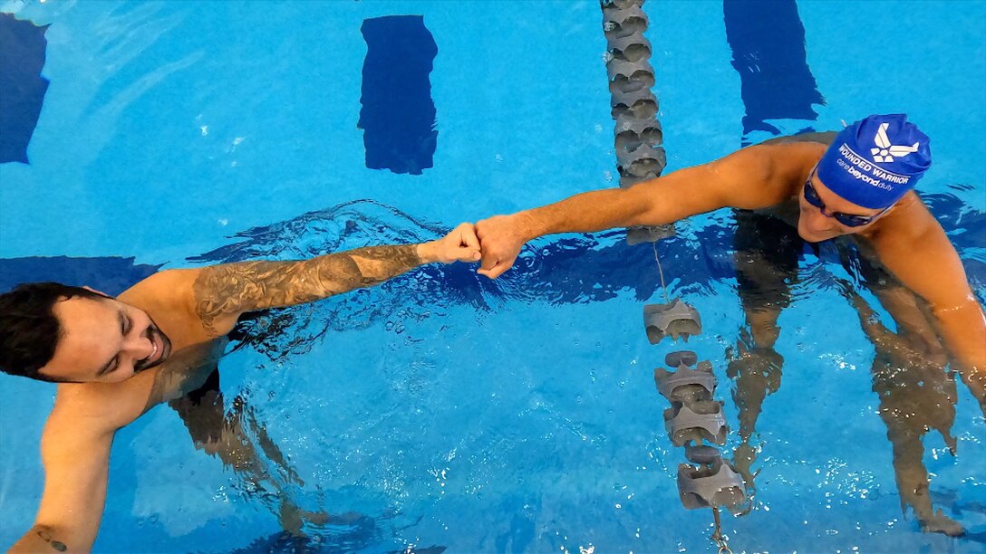 Swimmers bump fists during swimming practice.