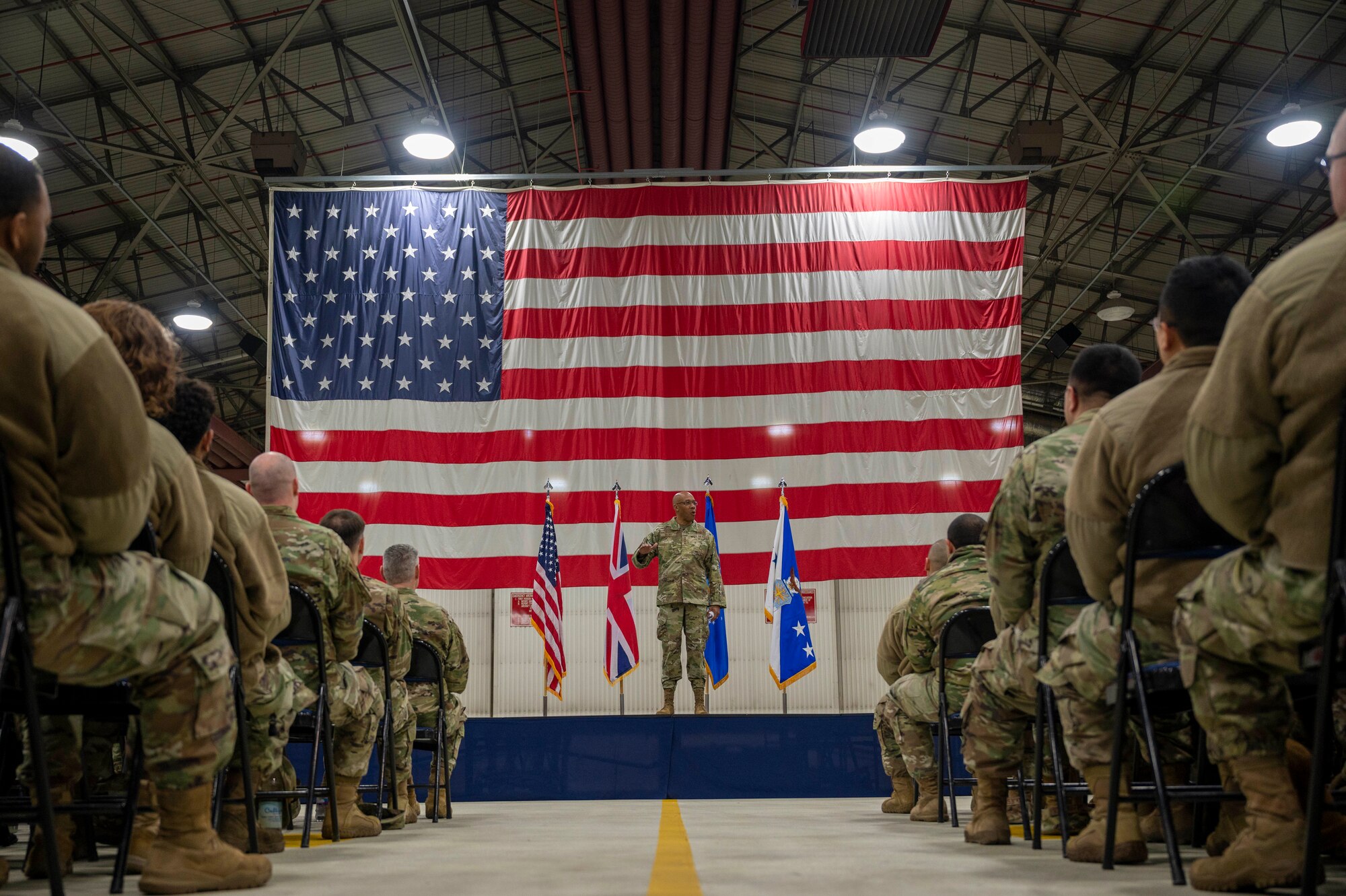 The Air Force Chief of Staff speaks to a crowd in front of a large flag