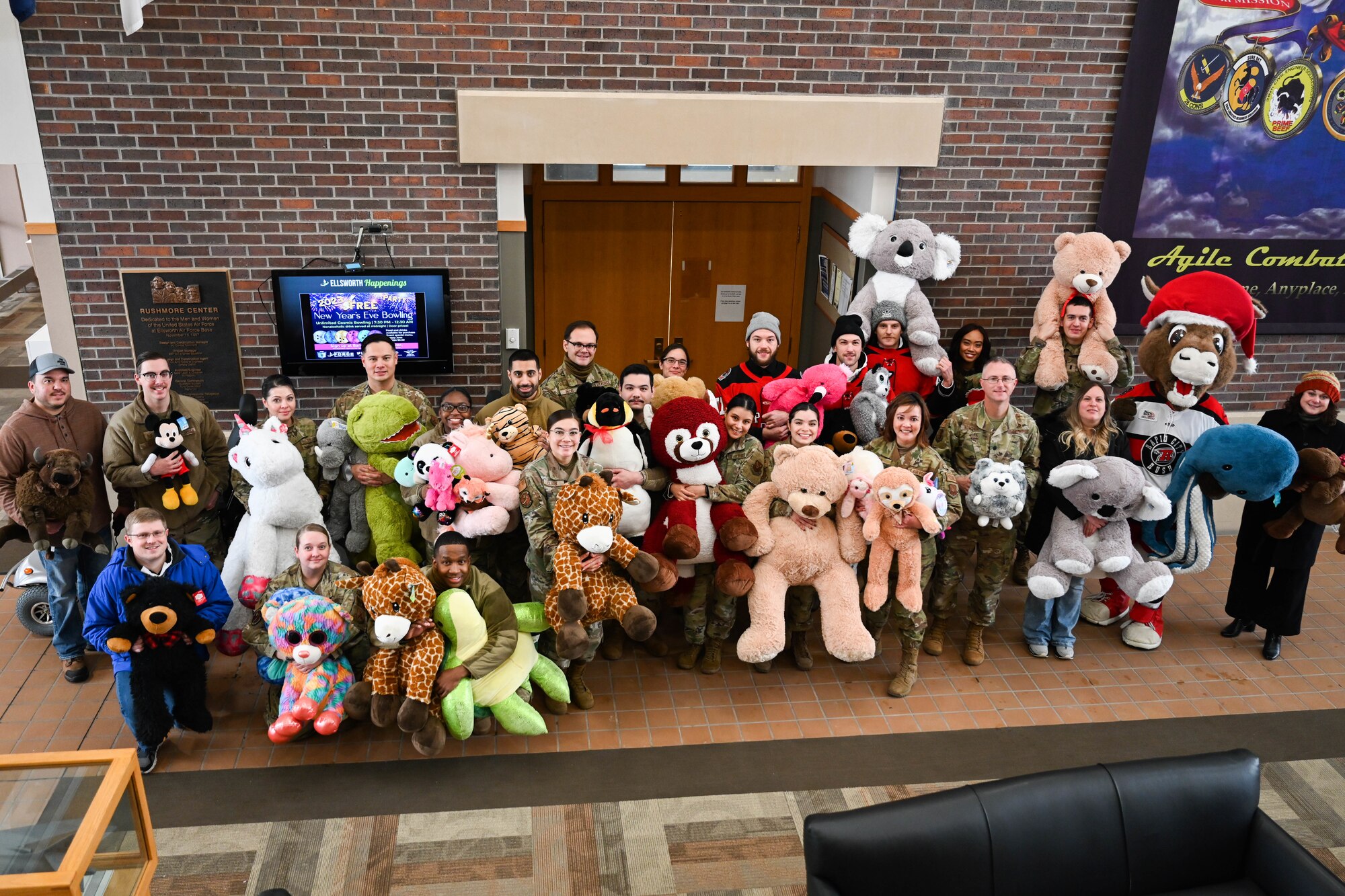 Members of the Rapid City Rush Hockey Team and Black Hills Energy gather with Airmen from the 28th Bomb Wing for a photo at Ellsworth Air Force Base, South Dakota, Dec. 21, 2022. Members of the Rapid City Rush Hockey Team and Black Hills Energy donated 250 teddy bears for military families who currently have a family member deployed. (U.S. Air Force photo by Airman 1st Class Dylan Maher)