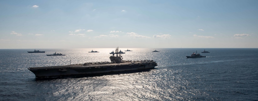 Ships steam in formation in the ocean.