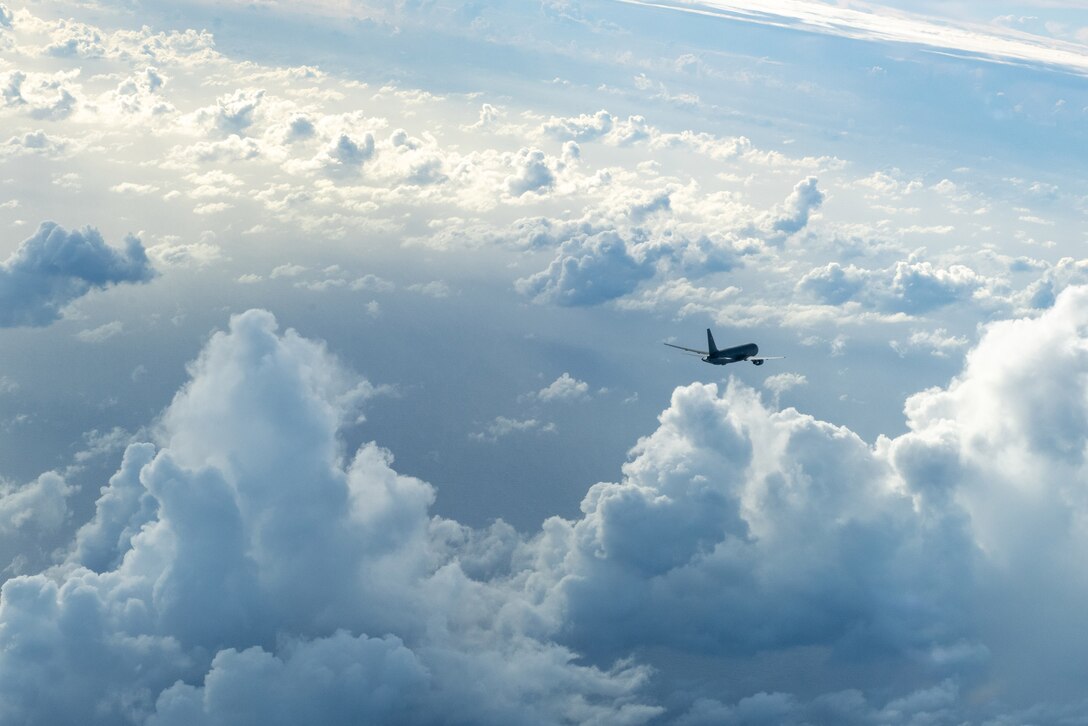 A military aircraft is shown flying above the clouds.