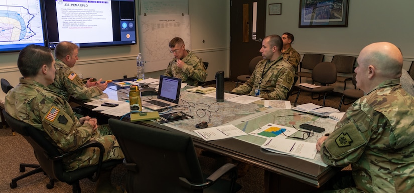 Members of the Pennsylvania National Guard Joint Operations Center staff participate in a conference call, from the Joint Operations Center conference room, with members across the commonwealth as part of a winter storm tabletop exercise designed to improve and validate domestic response procedures on Dec. 20, 2022, at Fort Indiantown Gap, Pa. (Pennsylvania National Guard photo by Wayne V. Hall) (This photo was altered to obscure an ID card)