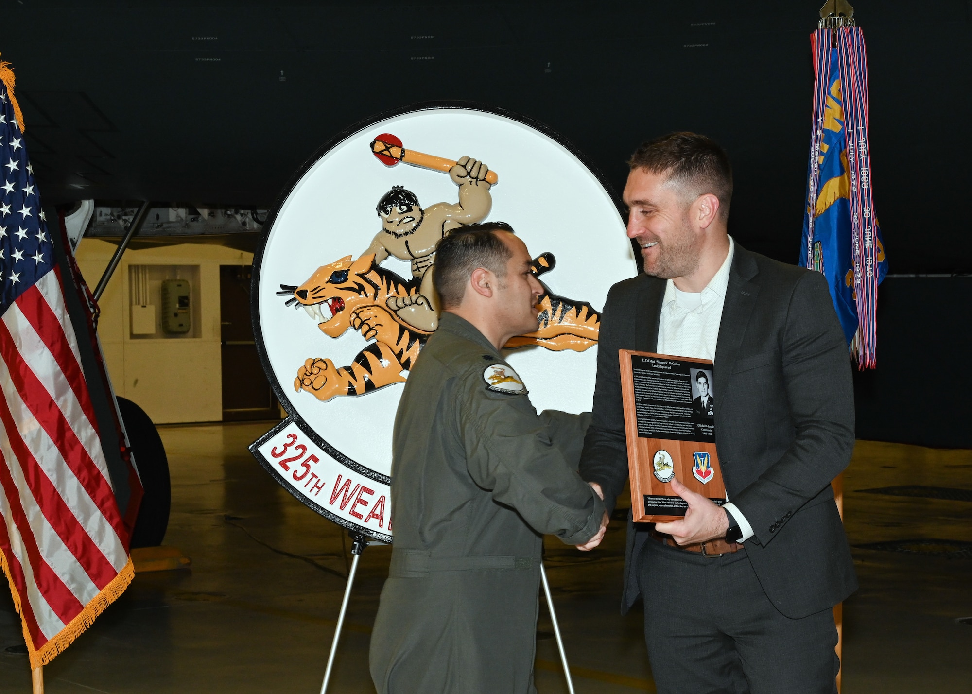 U.S. Air Force Lt. Col. Marcus Antonini, 325th Weapons Squadron commander, presents a commemorative plaque to Patrick McGeehan at Whiteman Air Force Base, Mo., Dec. 13, 2022. The plaque honors the legacy of McGeehan’s father Lt. Col. Mark McGeehan. (U.S. Air Force photo by Airman 1st Class Nash Truitt)