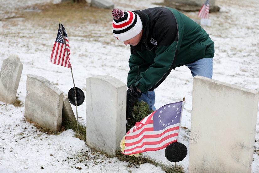 Elk Grove Village Mayor Craig Johnson lays a wreath on the grave of Revolutionary War Veteran Eli Skinner during a ceremony on Wreaths Across America Day, December 17, 2022, at the Elk Grove Cemetery, 25 miles northwest of Chicago.