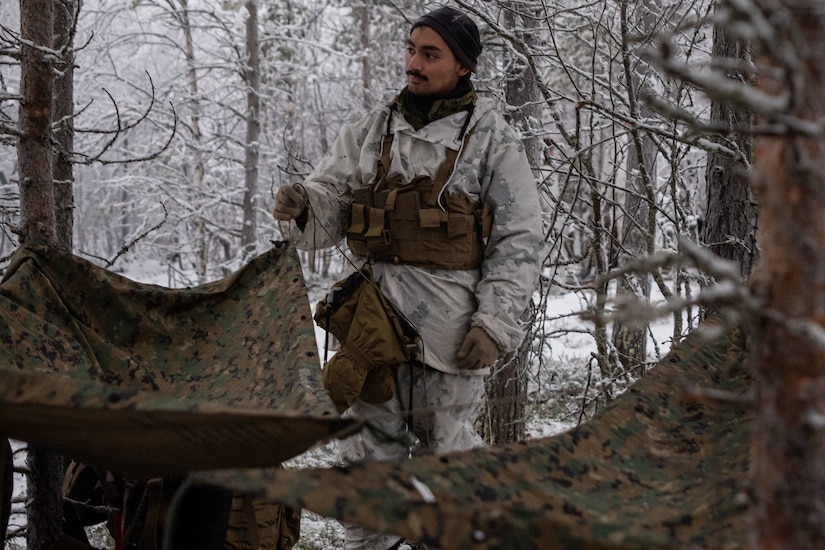 A man in military uniform sets up tent.