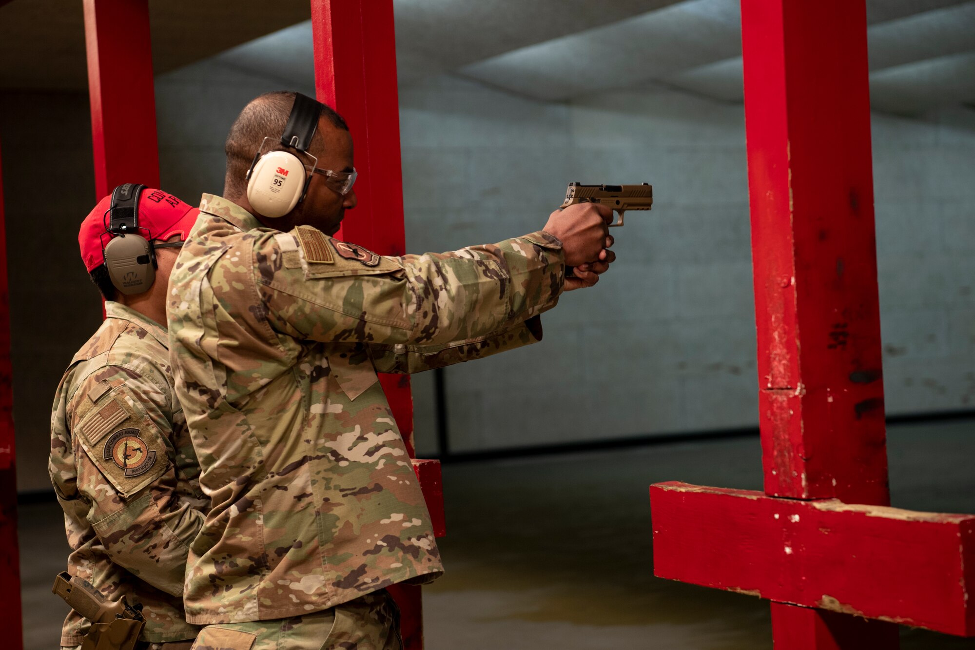 U.S. Air Force Chief Master Sgt. Alvin Dyer (right), 7th AF command chief, fires the M-18 pistol in the 51st Security Forces Squadron Combat Arms Training and Maintenance (CATM) firing range, Dec. 21, 2022, at Osan Air Base, Republic of Korea.