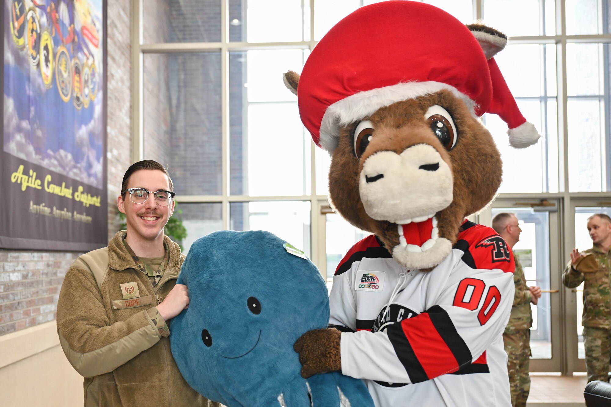 Tech Sgt. Alec Cope, 28th Comptroller Squadron noncommissioned officer in charge of financial analysis, poses for a photo with Nugget, Rapid City Rush Hockey Team mascot, at Ellsworth Air Force Base, South Dakota, Dec. 21, 2022. Members of the Rapid City Rush Hockey Team and Black Hills Energy donated 250 teddy bears for military families who currently have a family member deployed. (U.S. Air Force photo by Airman 1st Class Dylan Maher)