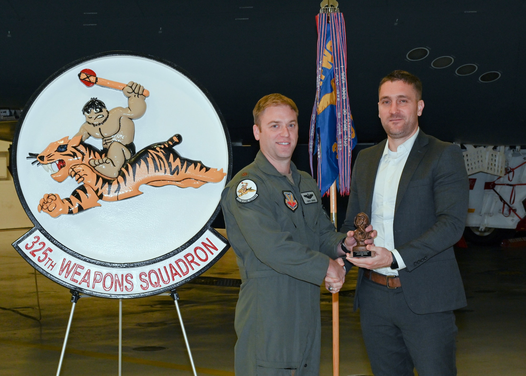 Patrick McGeehan, son of Lt. Col. Mark McGeehan, presents an award named for his father to Maj. William Jensen, assistant director of operations, 325th weapons squadron at Whiteman Air Force Base, Mo., Dec. 13, 2022. Jensen was selected for the inaugural ceremony for his leadership and innovation with the 325th WPS. (U.S. Air Force photo by Airman 1st Class Nash Truitt)