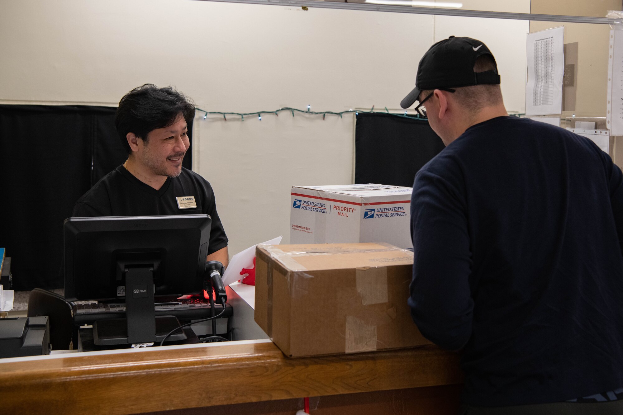 A postal clerk helps a customer.