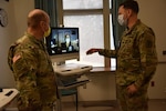 Col. (Dr) David De Blasio, deputy commander for medical services and Lt. Col. (Dr.) David Hostler, chief of pulmonary and critical care medicine at Womack Army Medical Center demonstrates how tele-critical care works. At the push of button Julia Powell, a nurse specialist assigned to San Diego, Joint Tele-Critical Care Network (JTCCN) responds ready to provide critical-care support, Dec. 2, 2022.