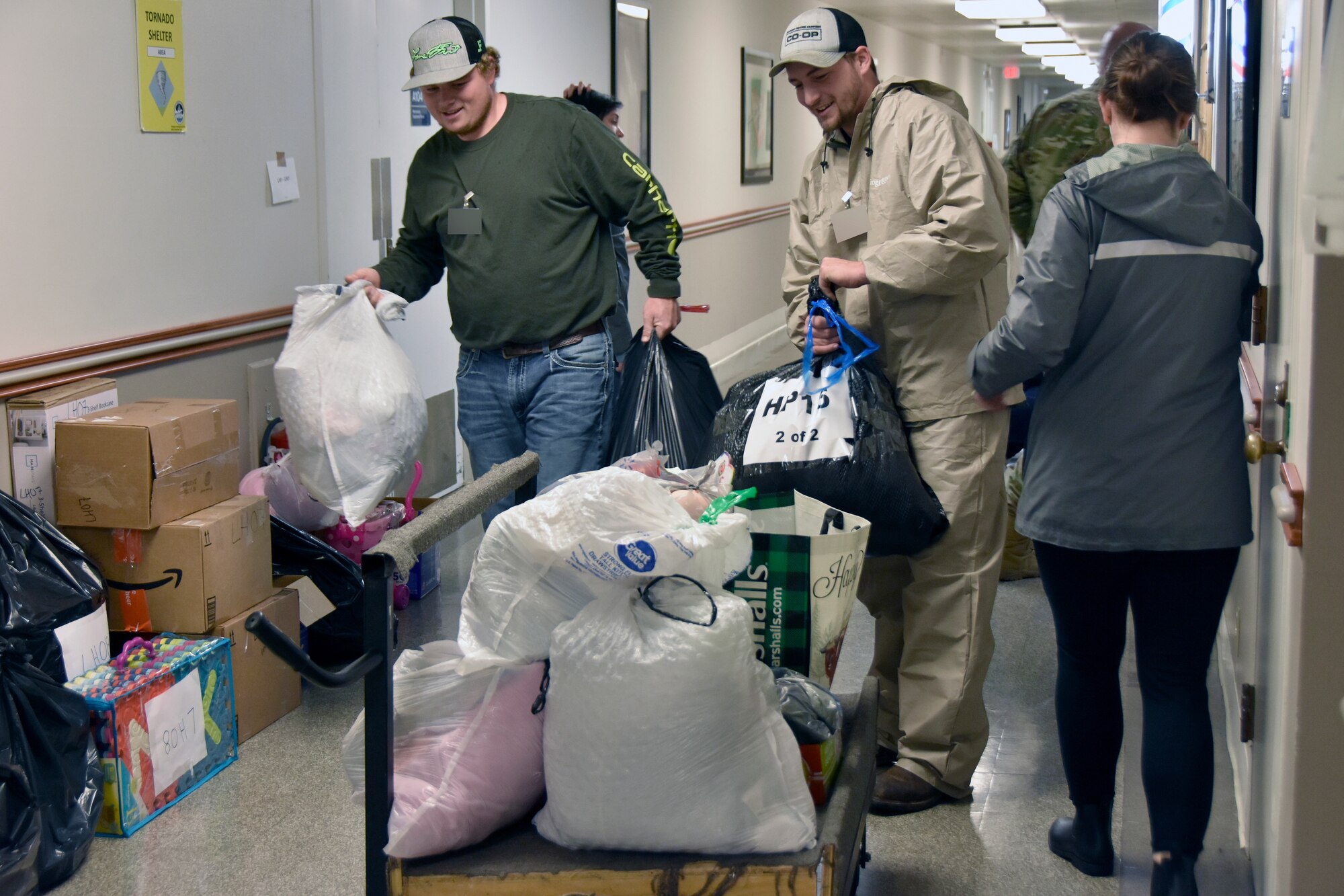 Austin Woods, left and Bradley Parks, center, volunteers with the Center for Family Development in Shelbyville, load gifts onto a cart for transport off Arnold Air Force Base, Tennessee, Dec. 14, 2022. Staff and volunteers from the center visited Arnold AFB to collect gifts purchased by Arnold personnel during the 2022 Arnold Engineering Development Complex Gift Sponsor toy drive, previously known as the AEDC Angel Tree. Members of the Arnold workforce sponsored more than 150 area children this year to provide them with gifts for Christmas. (U.S. Air Force photo by Bradley Hicks) (This image was altered by obscuring badges for security purposes.)