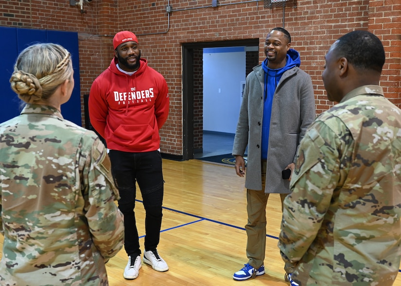 Extreme Football League D.C. Defenders defensive lineman Jesse Aniebonam and team vice president Lance Wesson speak with U.S. Air Force Col. Catherine "Cat" Logan and Command Chief Master Sgt. Clifford Lawton, Joint Base Anacostia-Bolling and 11th Wing commander and command chief, on JBAB, Washington, D.C., at the JBAB Fitness Center on Dec. 16, 2022. Engagements with sports teams in the greater D.C. area are one of the many ways JBAB connects with the surrounding communities. Strong community partnerships foster trust and support, bridging the military-civilian gap in experience and understanding. (U.S. Air Force photo by Tech. Sgt. Kayla White)