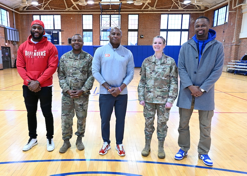 U.S. Air Force Col. Catherine "Cat" Logan and Command Chief Master Sgt. Clifford Lawton, Joint Base Anacostia-Bolling and 11th Wing commander and command chief Chief Master Sgt. Clifford Lawton pose for a group photo with members of the Extreme Football League D.C. Defenders team at the JBAB fitness center on Dec. 16, 2022, JBAB, Washington, D.C. Engagements with sports teams in the greater D.C. area are one of many ways JBAB connects with the surrounding communities. Strong community partnerships foster trust and support, bridging the military-civilian gap in experience and understanding. (U.S. Air Force photo by Tech. Sgt. Kayla White)