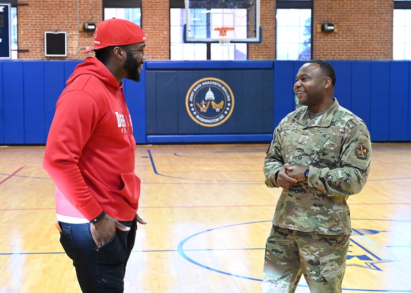 Command Chief Master Sgt. Clifford Lawton, Joint Base Anacostia-Bolling senior enlisted leader and 11th Wing command chief engages with Extreme Football League D.C. Defenders defensive lineman Jesse Aniebonam at the fitness center on Joint Base Anacostia-Bolling Fitness Center on JBAB, Washington, D.C., on Dec. 16, 2022. Engagements with sports teams in the greater D.C. area are one of the many ways JBAB connects with the surrounding communities. Strong community partnerships foster trust and support, bridging the military-civilian gap in experience and understanding. (U.S. Air Force photo by Tech. Sgt. Kayla White)
