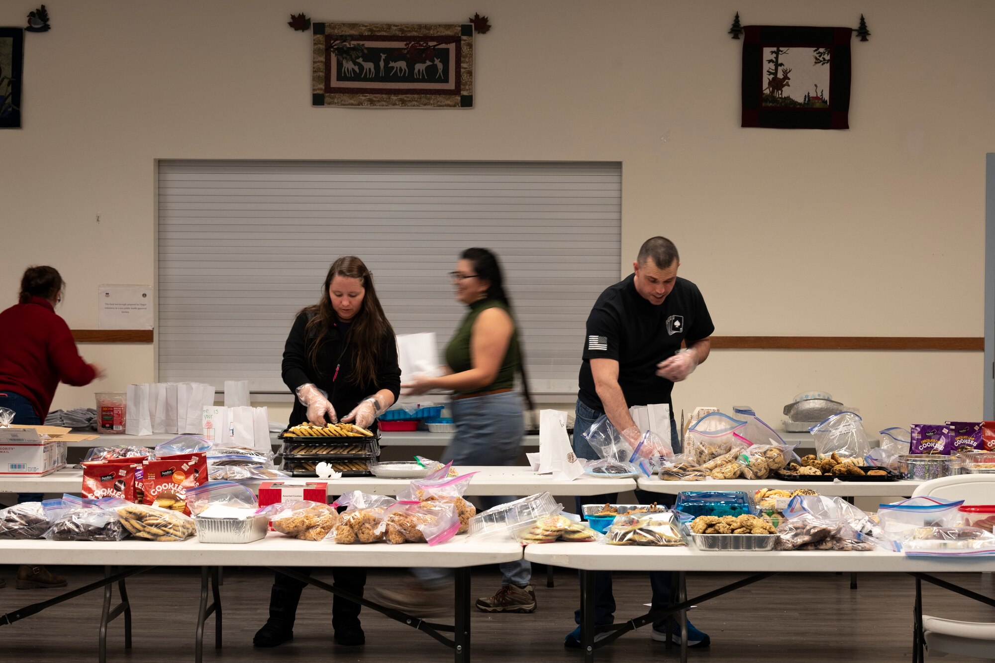 Long tables are topped with cookies being sorted by four individuals.