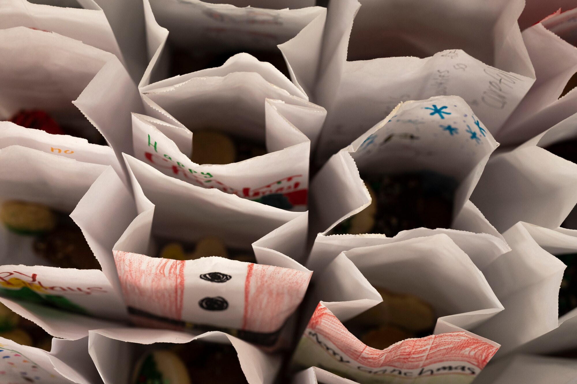 A birds-eye view of a dozen white paper bags filled with cookies.