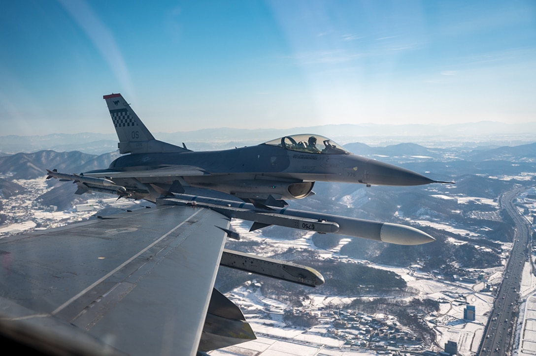 Military aircraft are shown flying over snowy terrain.