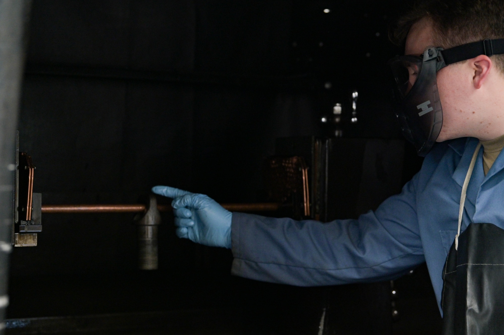 U.S. Air Force Tech. Sgt. Cody Dickerson, 23rd Maintenance Squadron nondestructive inspection supervisor, places a metal piece on a copper rod during an inspection at Moody Air Force Base, Georgia, Dec. 5, 2022. This magnetic particle inspection technique is used to detect cracks on different sizes of metal that require different levels of magnetism; the larger the piece of metal, the higher amperage it requires to create a stronger magnetic field. (U.S. Air Force photo by Senior Airman Rebeckah Medeiros)