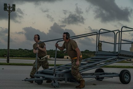 A photo Airmen pushing a maintenance stand on the flightline.