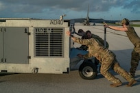 A photo of Airmen pushing a power cart on the flightline.