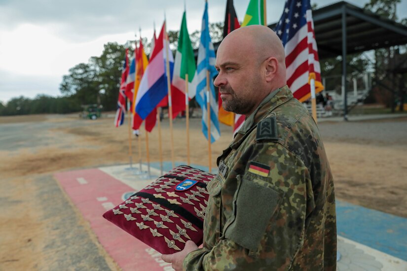 A German jump master (name withheld on request) watches as U.S. Civil Affairs Command (Airborne) Soldiers, alongside local Fort Bragg and partner nations' airborne Soldiers, complete a training and validation jump with German jump masters, during the the Randy Older Memorial Operation Toy drop 2.0, a combined airborne training event held from 4-12 DEC 2022 to increase joint airborne proficiency and enhance community relations. By jumping with the allied partners, Soldiers earn foreign jump wings that can be worn on their dress uniforms.