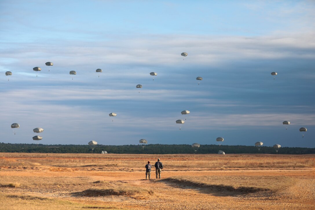 U.S. Civil Affairs Command (Airborne) Soldiers watch from Sicily Drop Zone, Fort Bragg, North Carolina, as their paratroopers, alongside local Fort Bragg and partner nations' airborne Soldiers, complete one of many training and validation jumps during the the Randy Older Memorial Operation Toy drop 2.0, a combined airborne training event held from 4-12 DEC 2022 to increase joint airborne proficiency and enhance community relations.