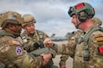 Brig. Gen. Dean Thompson (center), commanding general – 353rd Civil Affairs Command, looks on as Maj. Gen. Isaac Johnson, Jr. (left), commanding general, U.S. Army Civil Affairs and Psychological Operations Command (Airborne) exchanges greetings with one of the allied partner jump masters during the Randy Older Memorial Operation Toy drop 2.0, a combined airborne training event at Fort Bragg, NC, held from 4-12 DEC 2022 and designed to increase joint airborne proficiency while enhancing community relations.