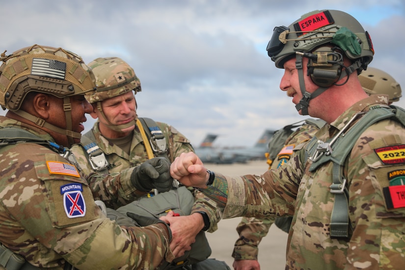 Brig. Gen. Dean Thompson (center), commanding general – 353rd Civil Affairs Command, looks on as Maj. Gen. Isaac Johnson, Jr. (left), commanding general, U.S. Army Civil Affairs and Psychological Operations Command (Airborne) exchanges greetings with one of the allied partner jump masters during the Randy Older Memorial Operation Toy drop 2.0, a combined airborne training event at Fort Bragg, NC, held from 4-12 DEC 2022 and designed to increase joint airborne proficiency while enhancing community relations.