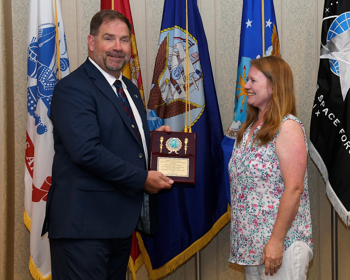 Man holding plaque next to female in a group photo.