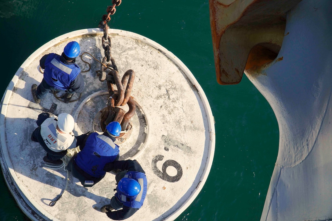 Four sailors stand on a buoy.