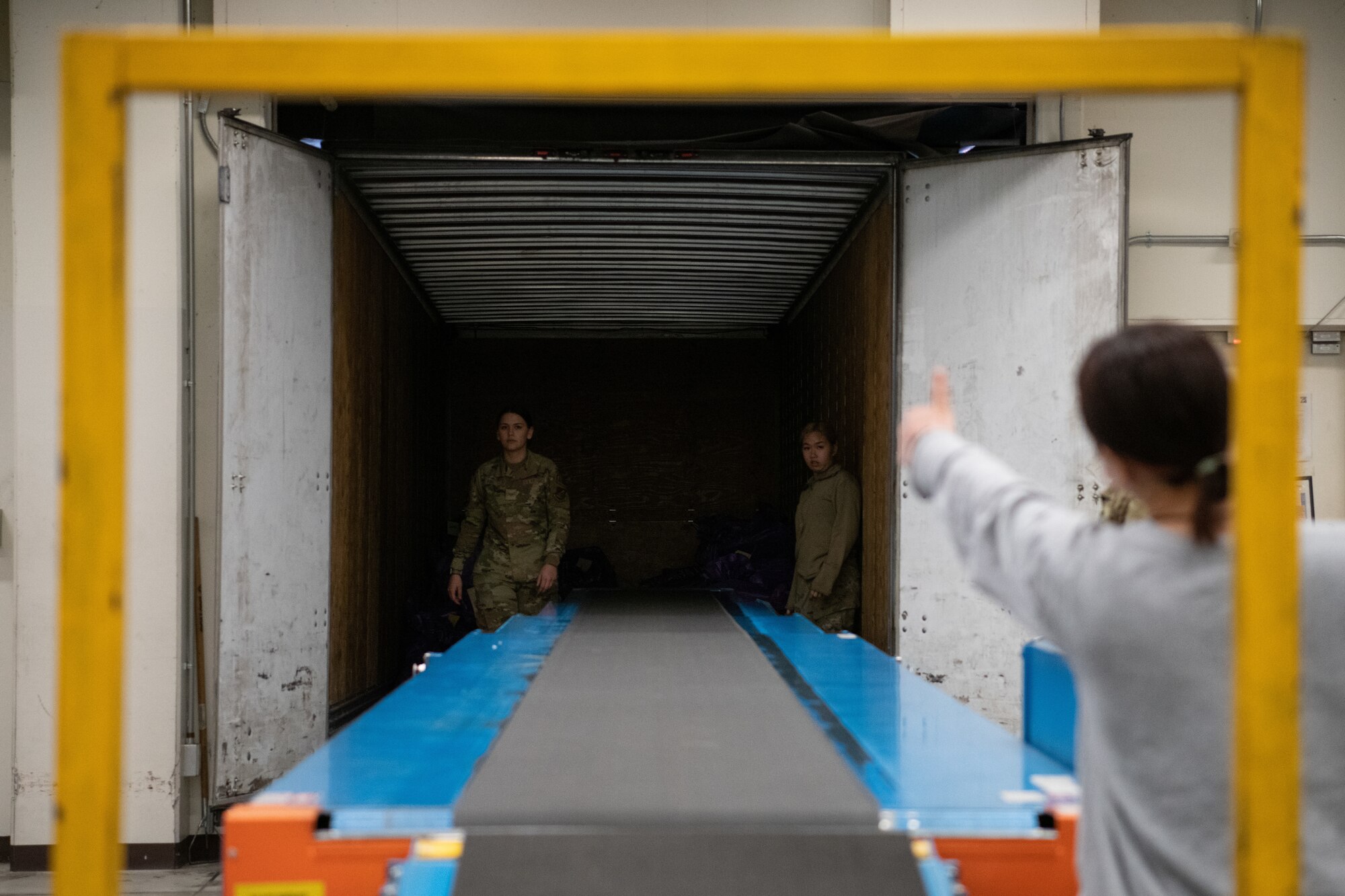 Airmen receive a thumbs up to load packages down a conveyer belt