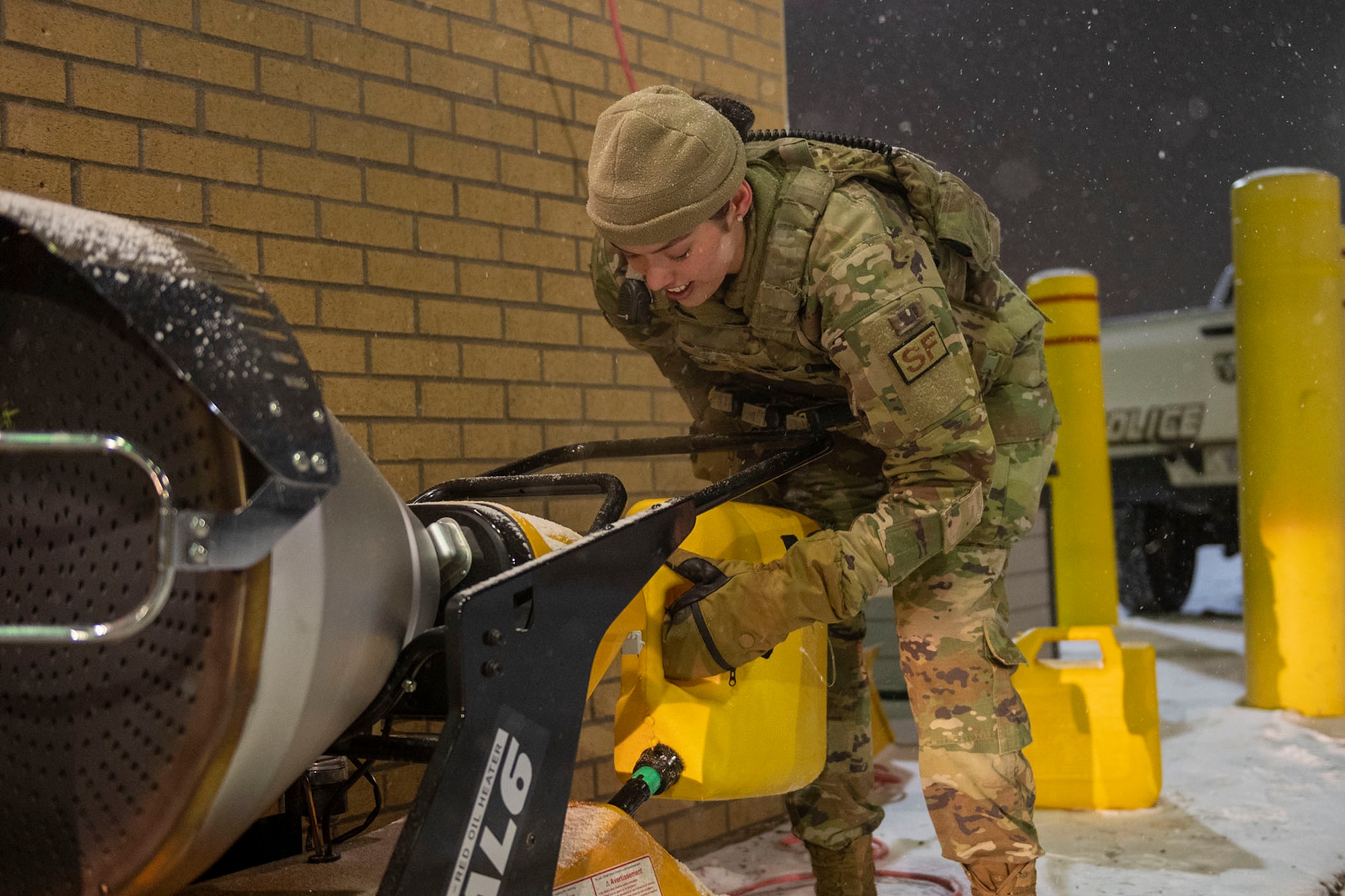 Airman 1st Class Elissa Yaag, 341st Security Forces Squadron defender refills a mobile-heater at the main gate of Malmstrom Air Force Base, Mont., due to sub-zero weather conditions, Dec. 20, 2022. Yaag and other defenders stand guard on the gate, 24/7, regardless of  dangerous weather conditions in support of Malmstrom's crucial mission. (Photo by Airman 1st Class Elijah Van Zandt)