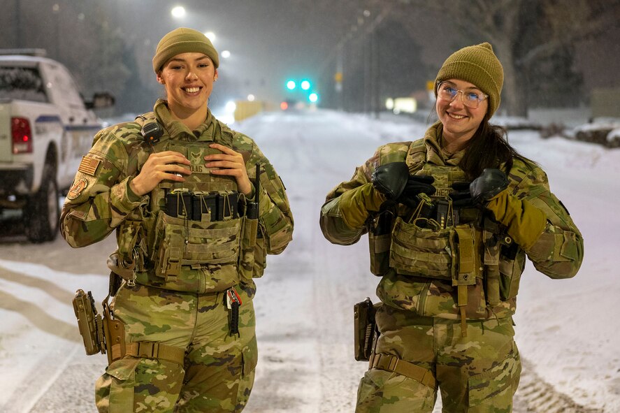 Airman 1st Class Elissa Yaag, left, and Airman 1st Class Abbigail Feathers, 341st Security Forces Squadron defenders, pose for a photo at the main gate of Malmstrom Air Force Base, Dec. 20, 2022. 
Defenders stand guard at the base 24/7 and ensure, in any weather condition, that no unauthorized personnel enter the installation. (U.S. Air Force photo by Airman 1st Class Elijah Van Zandt)