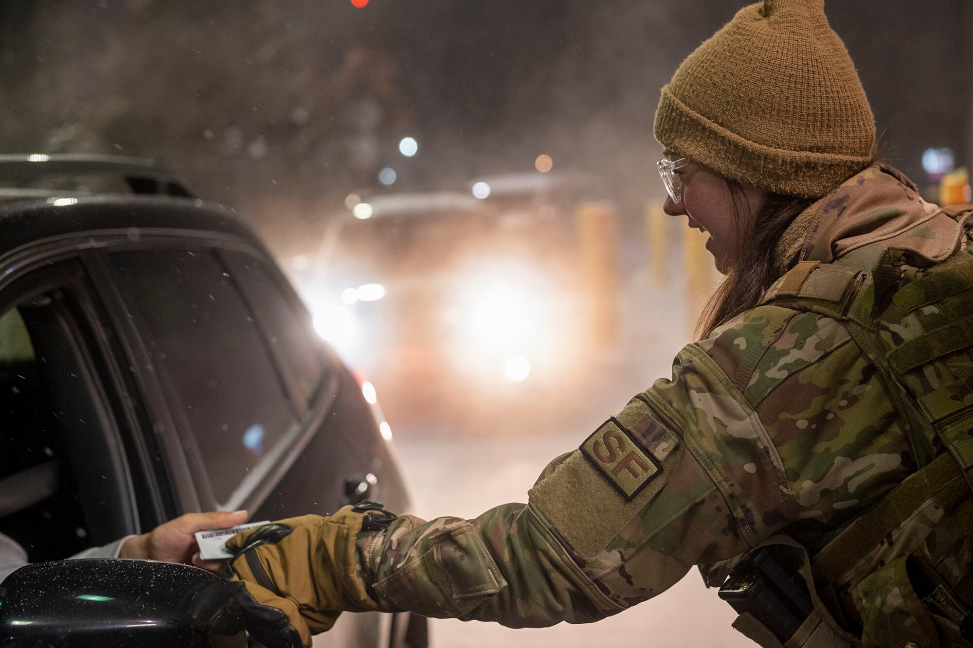 Airman 1st Class Abbigail Feathers, 341st Security Forces Squadron defender, verifies identification cards at the main gate at Malmstrom Air Force Base, Mont., Dec. 20, 2022.  Feathers and other defenders defend the gate of the installation 24/7 and in any weather condition. (U.S. Air Force photo by Elijah Van Zandt)