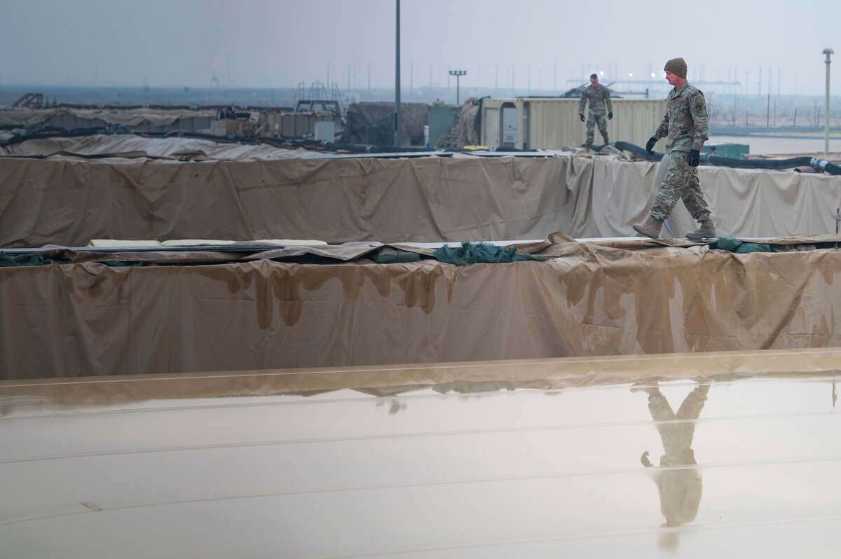 From right, U.S. Air Force Staff Sgt. Justin Poff, 386th Expeditionary Logistics Readiness Squadron fuels facilities South Storage NCOIC, prepares to install a new fuel bladder at Ali Al Salem Air Base, Kuwait, Dec. 22, 2022. Aerial porters, maintainers and 386th Air Expeditionary Wing leadership came out to the fuel storage area to help install a new fuel bladder to be used by the 386th AEW and its mission partners. (U.S. Air Force photo by Staff Sgt. Dalton Williams)
