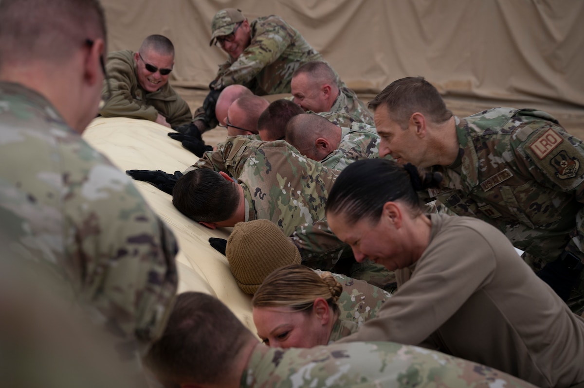 386th Air Expeditionary Wing Airmen unroll a fuel bladder during an installation at Ali Al Salem Air Base, Kuwait, Dec. 22, 2022. Leadership from the 386th AEW and Airmen from multiple 386th Expeditionary Logistics Readiness Squadron organizations came out to the fuel storage area to help install a new fuel bladder. (U.S. Air Force photo by Staff Sgt. Dalton Williams)
